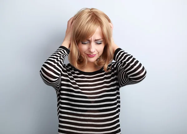 Depressed young blond woman with headache holding head the hands