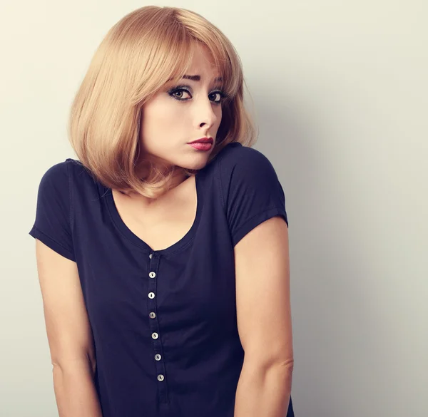 Confused young casual woman with blond hair. Toned closeup portr