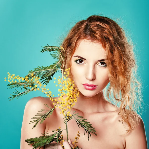 Portrait of a pretty girl with mimosa flowers.