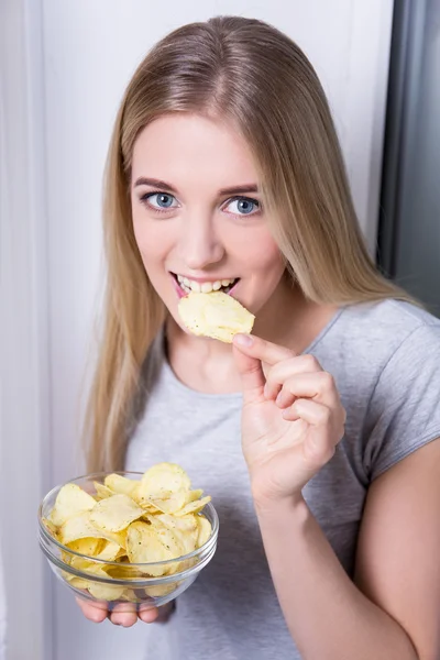 Portrait of happy young woman eating chips