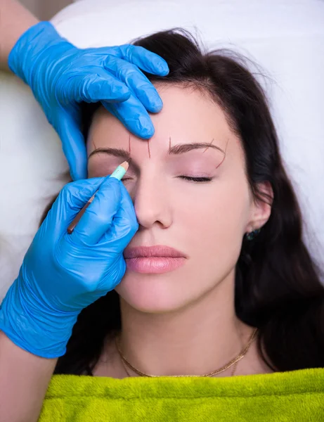 Cosmetician preparing a woman for permanent eyebrow make up