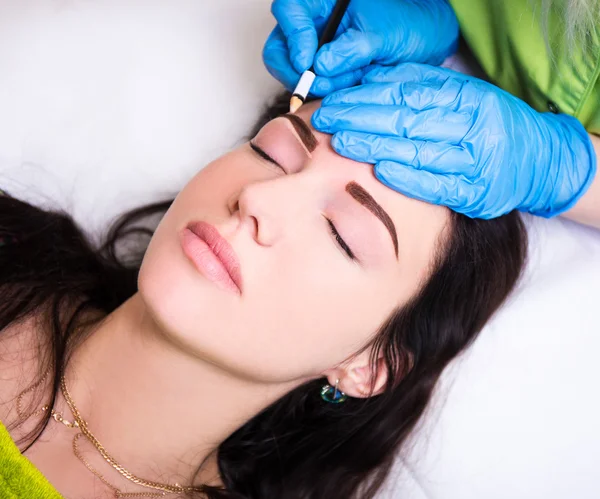 Permanent eyebrow make up - beautician preparing woman for proce