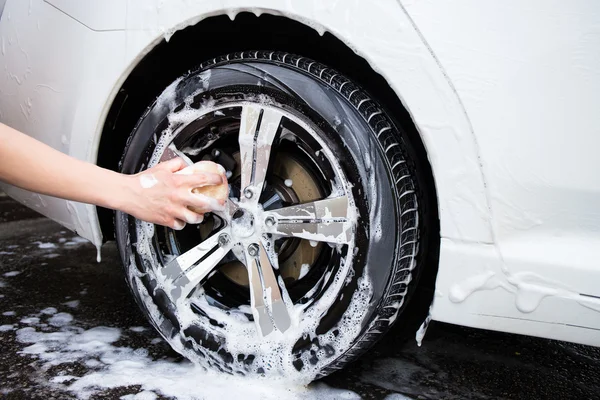 Male hand with sponge washing car wheel