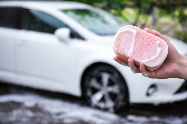 Handle car wash concept - hand with sponge and car on background