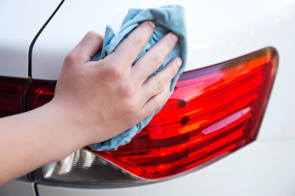 Male hand washing car lights with microfiber cloth