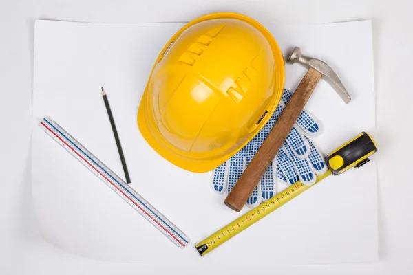 Yellow builder's helmet and work tools over white