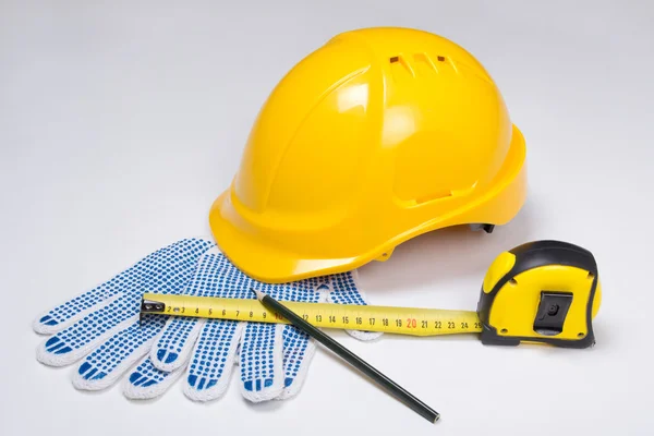 Builder's tools - helmet, work gloves, pen and measure tape ove