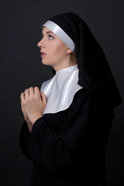 Religion concept - young woman nun praying over grey