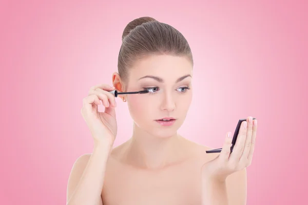 Portrait of young beautiful woman applying mascara on her eyelas