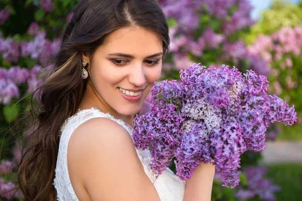 Portrait of beautiful bride with big bouquet of lilac flowers