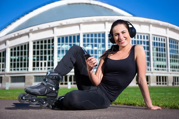 Happy woman in roller skates sitting and listening music