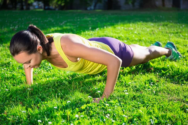 Beautiful woman doing push up exercise in park