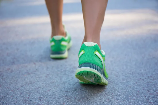 Close up of female legs in sporty shoes running on road