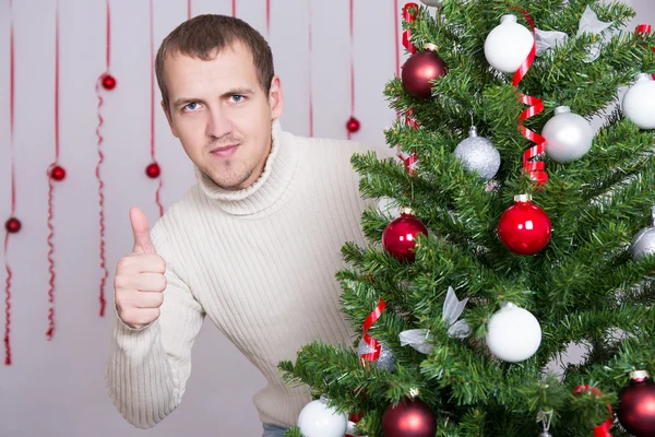 Portrait of handsome man thumbs up and  decorated Christmas tree