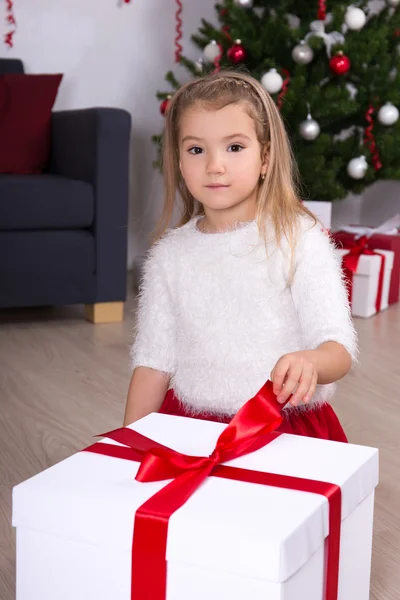 Portrait of little girl opening big gift box near Christmas tree