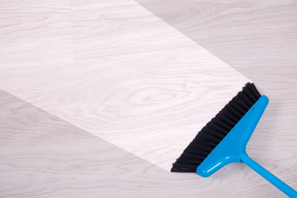 Cleaning concept - blue broom sweeping floor