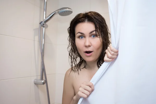 Beautiful surprised woman covering her body with curtain in show