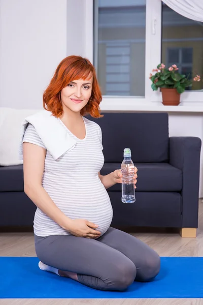 Happy pregnant woman relaxing after training at home