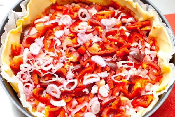 Pizza with vegetables and sausages in process of preparation