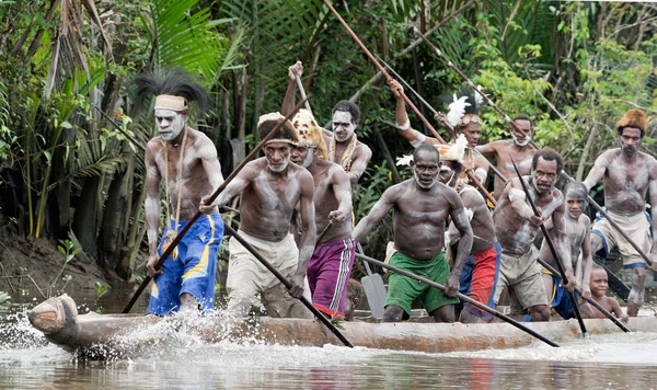 Asmat men paddling in their dugout canoe
