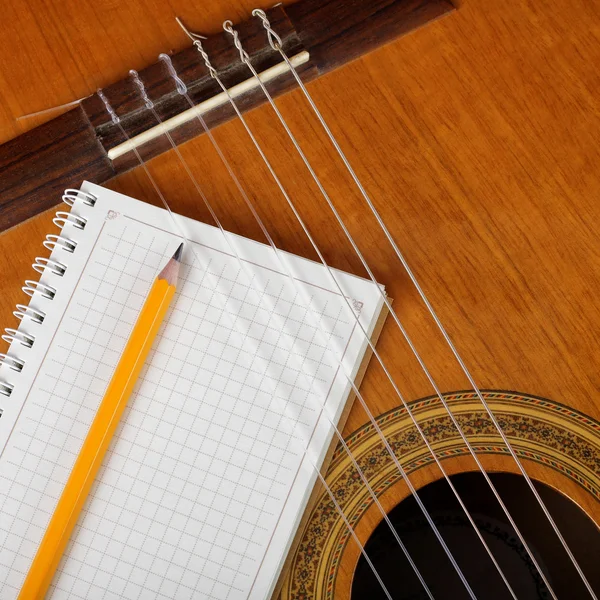 Musical instruments - the Acoustic guitar and a notebook.
