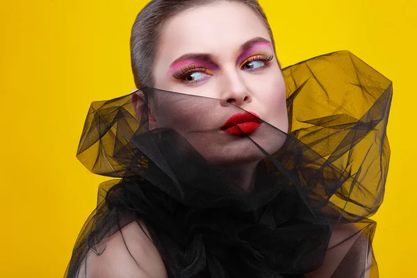 Portrait of sexual young girl in a black veil on a yellow background