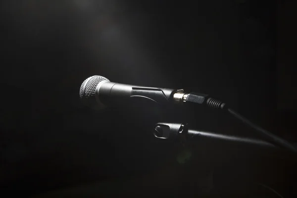 Black microphone on black dark background.