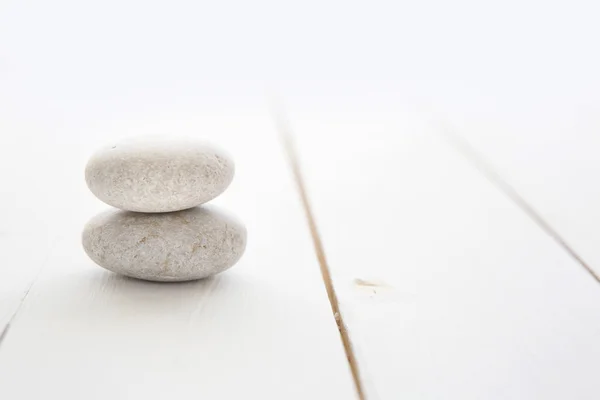 Zen stones on white wooden background.