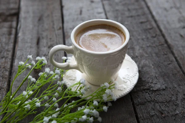 Cup of black coffee and white flowers on the table