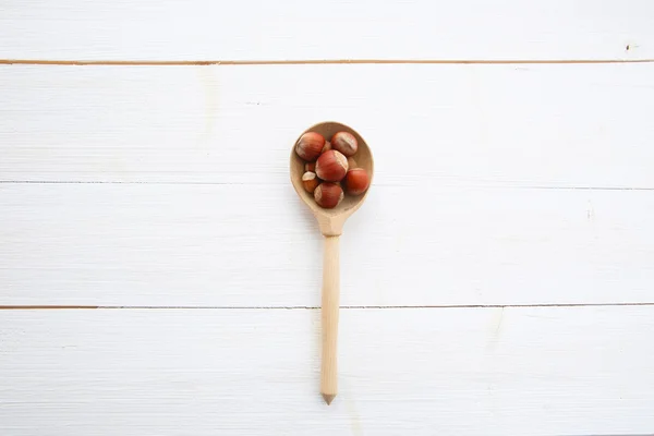 Hazelnuts in spoon on white wooden table