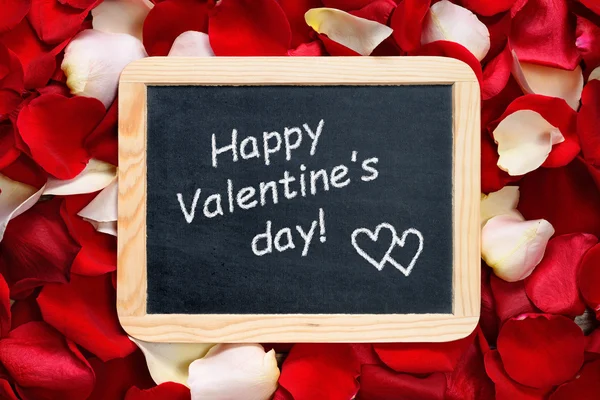 Happy Valentines day! text on blackboard on background of rose petals