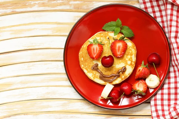 Breakfast pancakes with berries (strawberry, cherry, banana), funny face