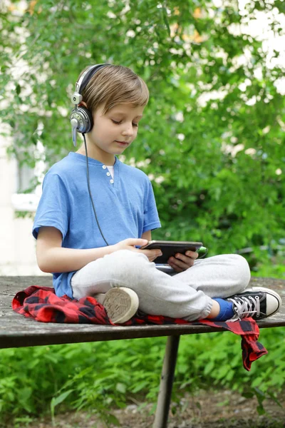 The boy listens to music outside in the park