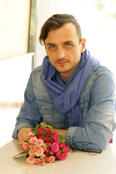 Young man in  cafe with a bouquet of roses