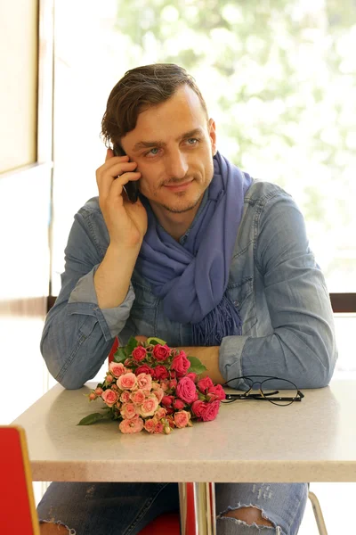 Young man in  cafe with a bouquet of roses