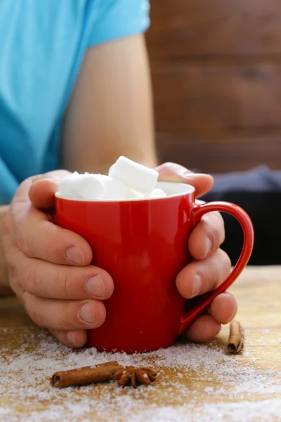 Man holding a mug hot cocoa with marshmallows, winter Christmas drink