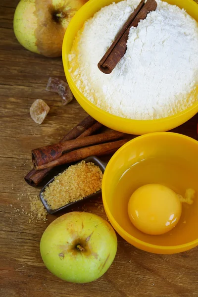 Ingredients for baking apple pie (flour, egg, sugar, cinnamon, apples)