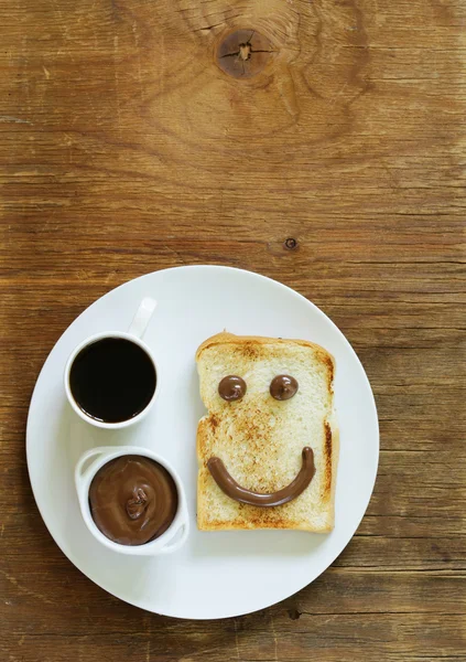 Breakfast serving funny face on the plate (toast, chocolate spread and coffee)
