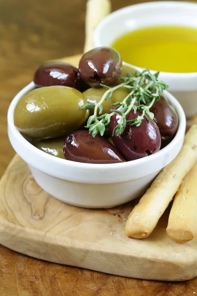 Black and green olives in oil with herbs