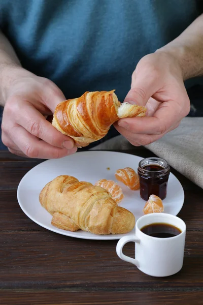 Man eating a croissant with jam for breakfast