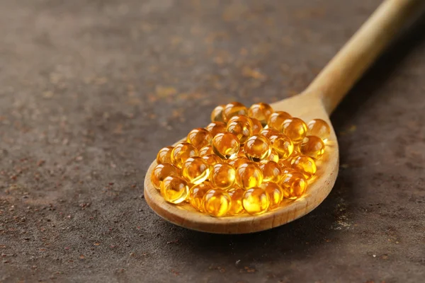 Food supplement of fish oil capsules in a wooden spoon - healthy food