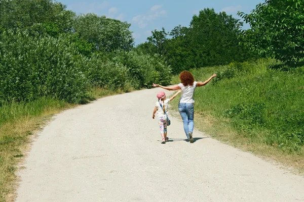 Mother and daughter walking by rural road