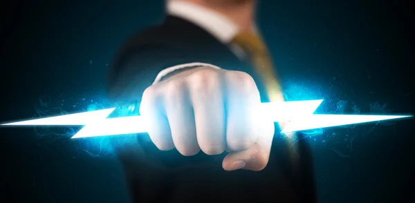 Business man holding glowing lightning bolt in his hands