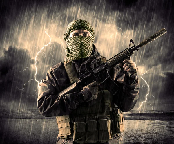 Dangerous armed terrorist with mask and gun in a thunderstorm wi