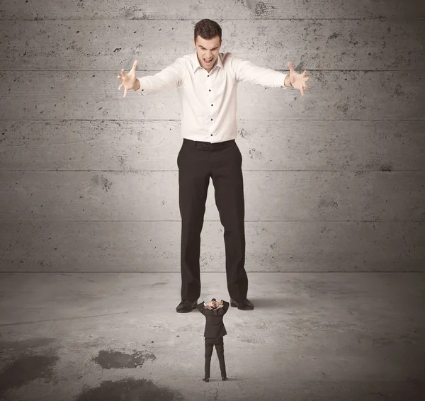 Huge business guy looking at small coworker