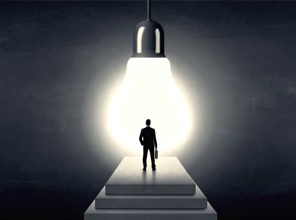 Man standing on a step in front of a huge light bulb