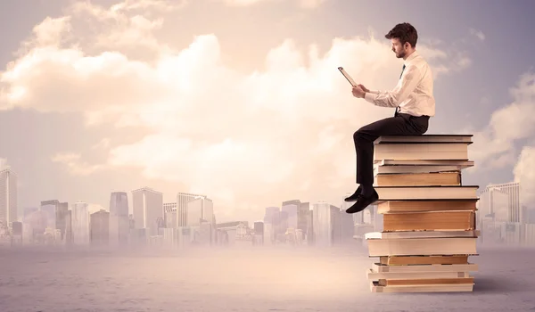 Businessman with laptop sitting on books