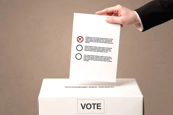 Close up of male hand putting vote into a ballot box