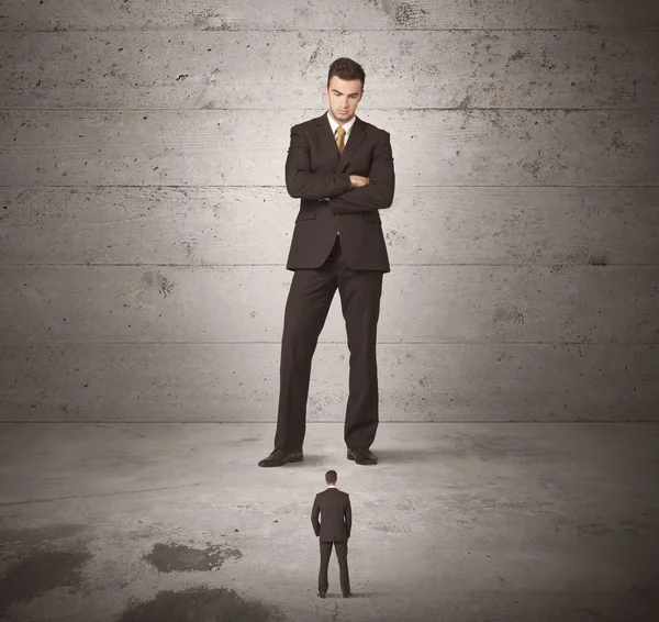 Huge business guy looking at small coworker