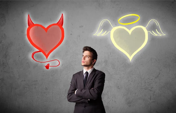 Businessman standing between angel and devil hearts